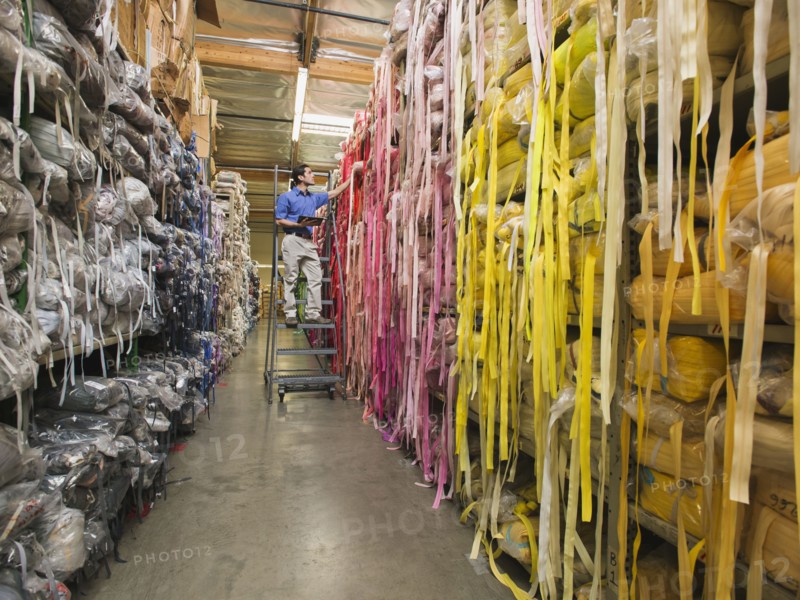 Mixed race worker examining fabric in textile factory