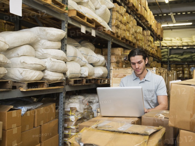 Mixed race worker using laptop in textile factory