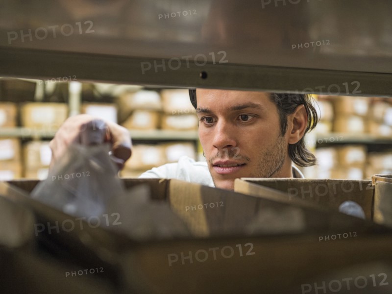 Mixed race worker examining bin in textile factory