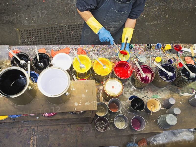 Hispanic worker mixing paint in workshop