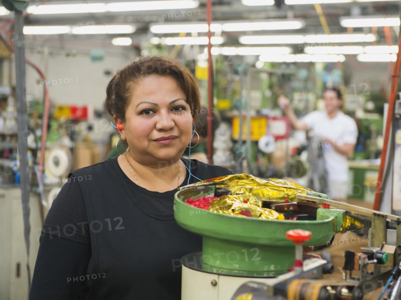 Hispanic worker operating machinery in textile factory
