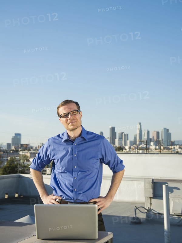 Caucasian businessman using laptop on urban rooftop