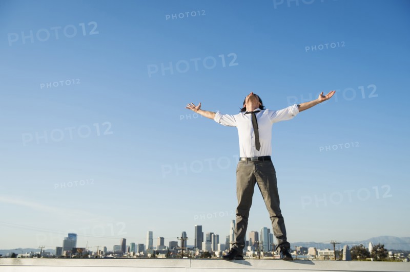 Mixed race businessman standing on urban rooftop