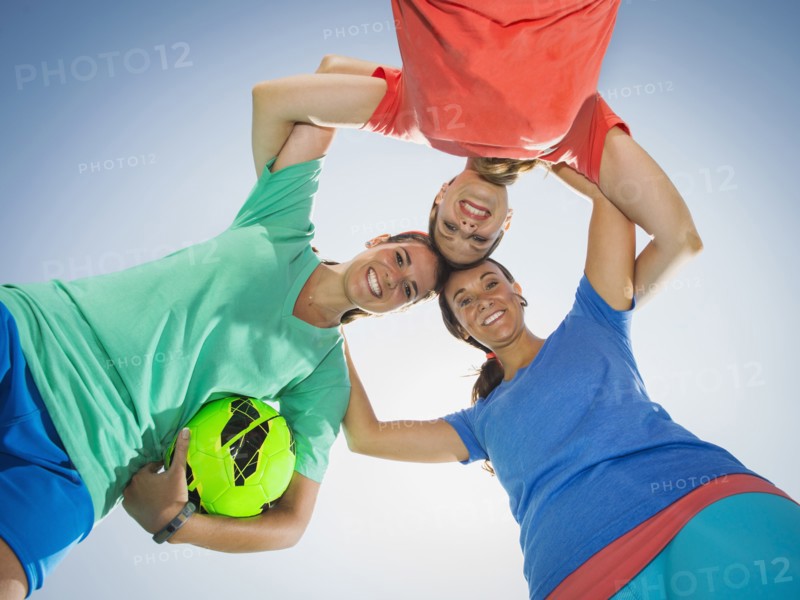 Caucasian women smiling in huddle under blue sky