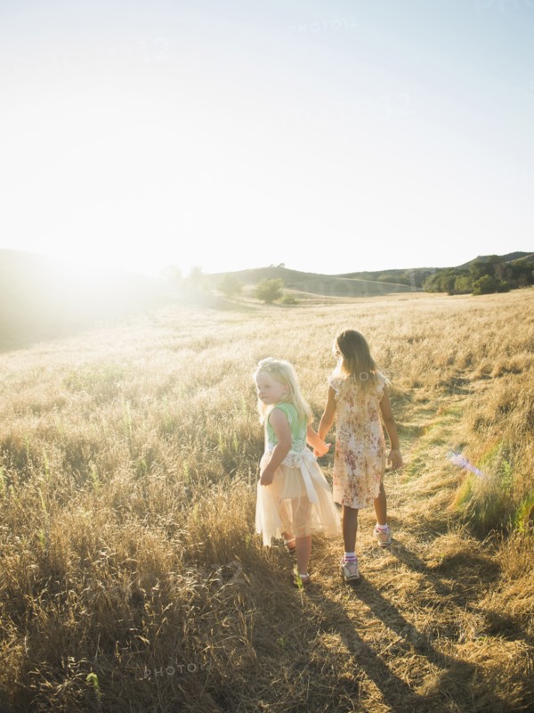 Caucasian girls holding hands in rural field