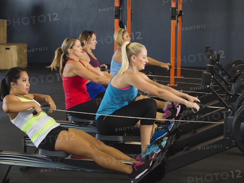 Women using rowing machines in gym