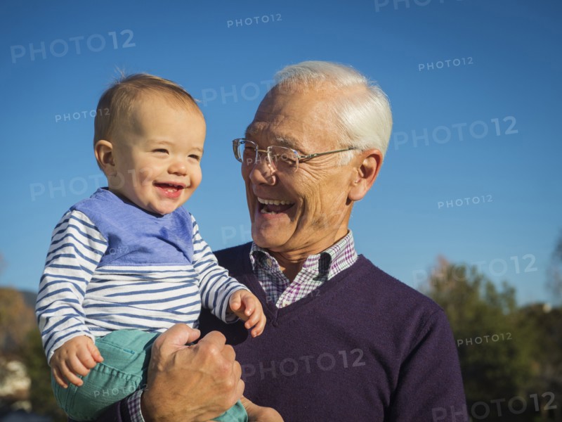Older man holding grandson outdoors