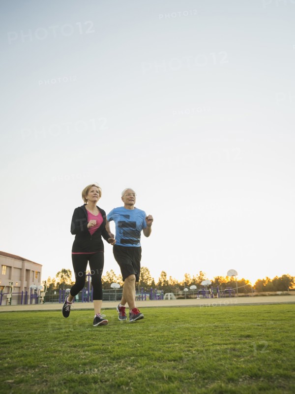 Older couple jogging together in urban park