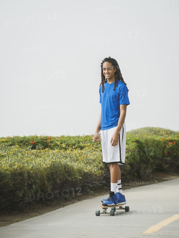 Black teenage boy riding skateboard on street