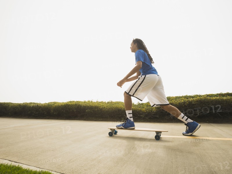 Black teenage boy riding skateboard on street