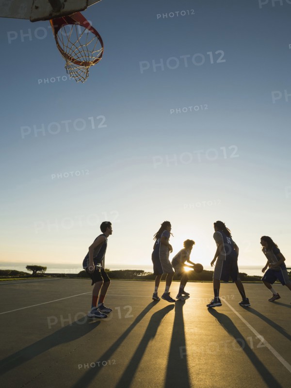Back lit basketball teams playing on court