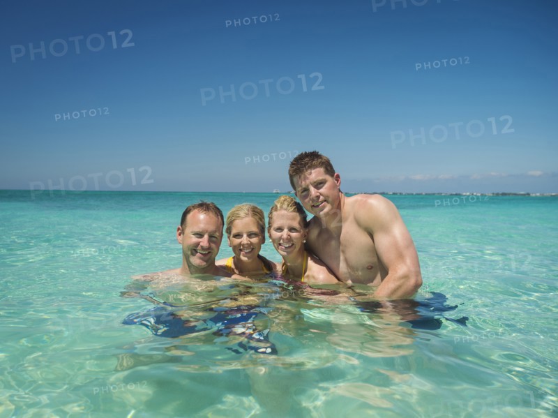 Caucasian couples smiling together in tropical ocean