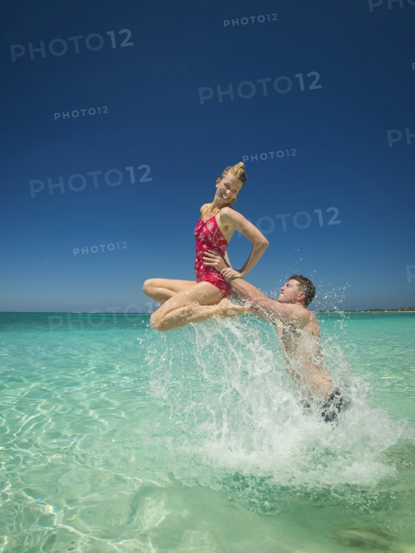 Caucasian couple playing in water in tropical ocean