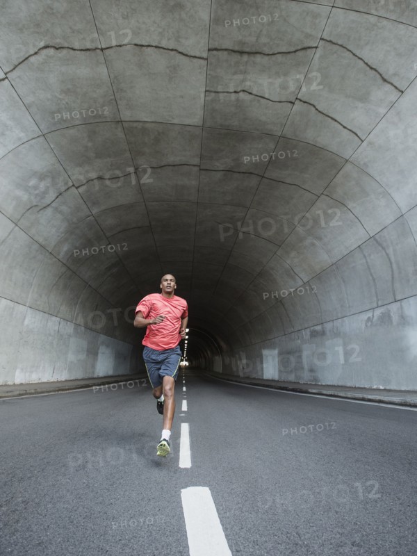 Black man running in urban tunnel