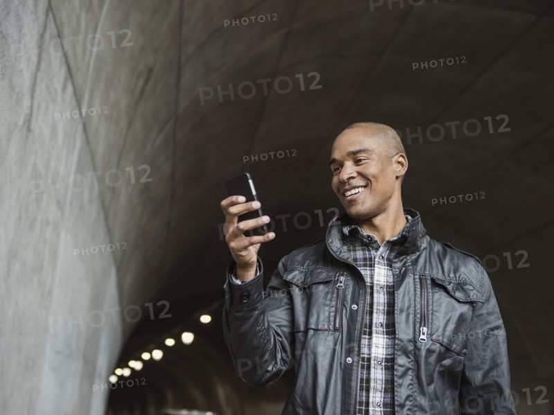 Black man using cell phone in urban tunnel