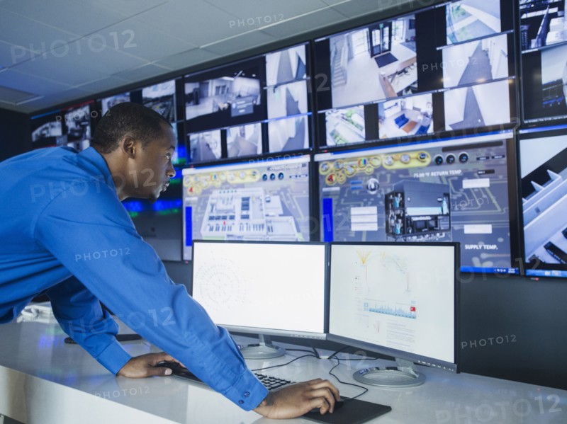 Black security officer watching surveillance cameras