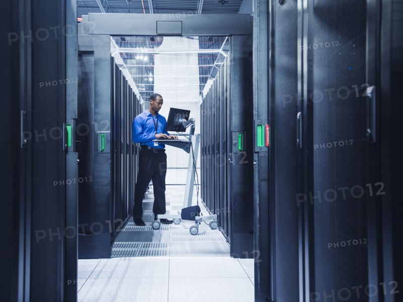 Black businessman using computer in server room