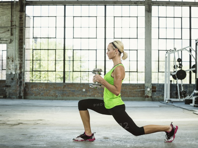 Caucasian woman lifting weights in warehouse gym
