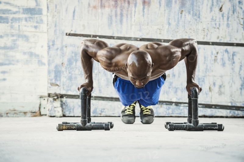 Black man doing push ups in warehouse