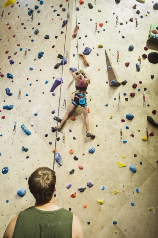 Caucasian man belaying climber at indoor rock wall