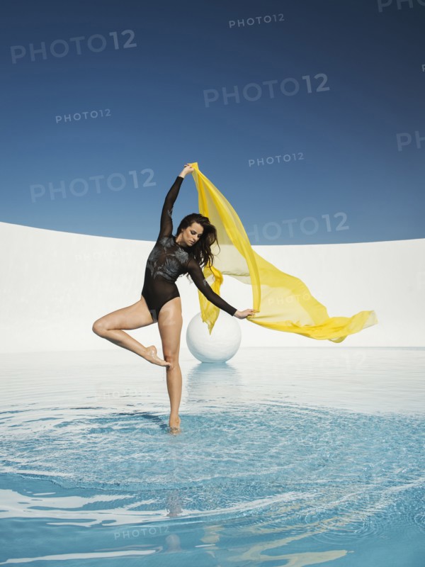 Caucasian woman dancing with fabric on water surface