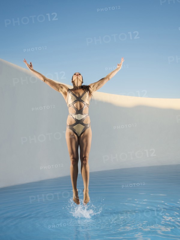 Caucasian woman jumping on swimming pool