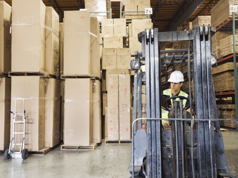 Caucasian worker driving forklift in warehouse