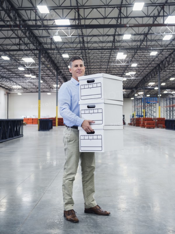 Caucasian businessman carrying boxes in empty warehouse