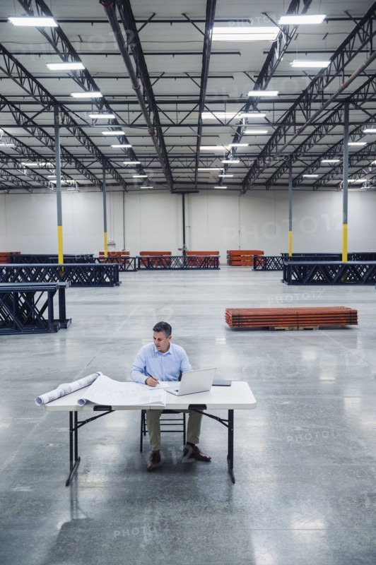 Caucasian architect reading blueprints in warehouse