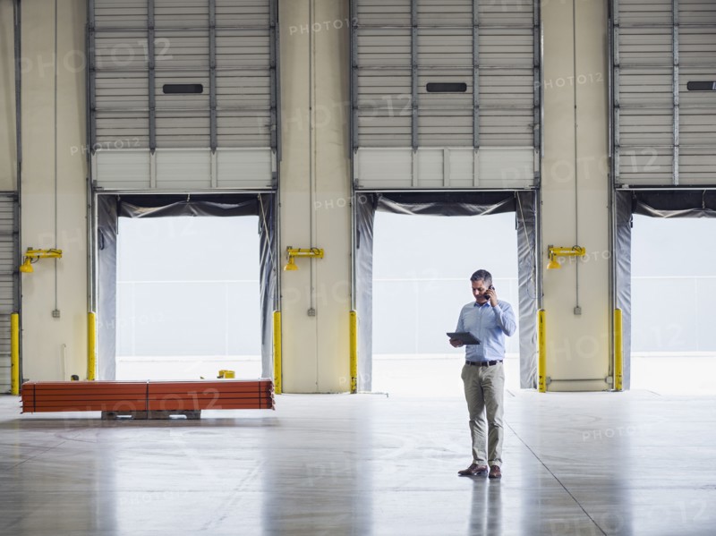 Caucasian businessman talking on cell phone in warehouse
