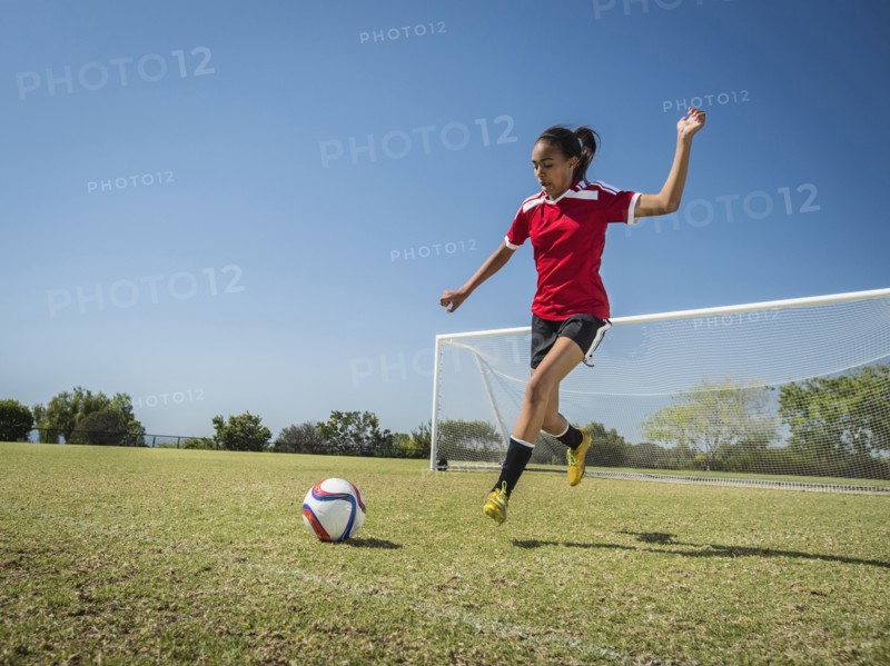 Mixed race soccer player kicking ball on field