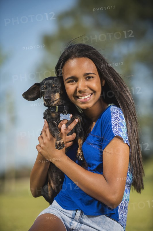 Mixed race girl hugging dog outdoors