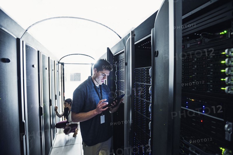 Technician using digital tablet in server room