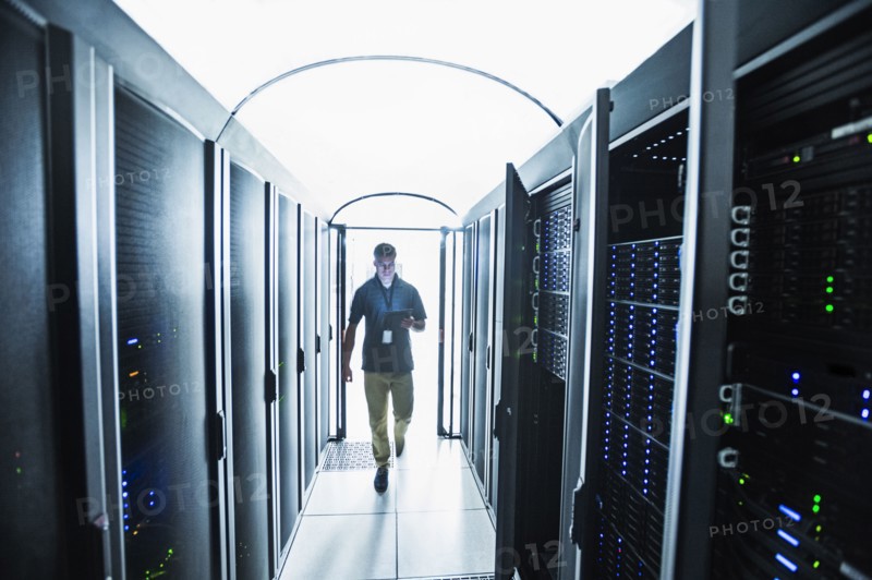 Hispanic technician carrying digital tablet in server room