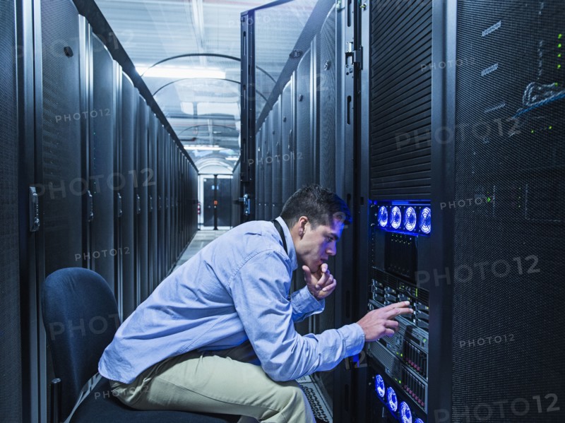 Hispanic technician checking technology in server room