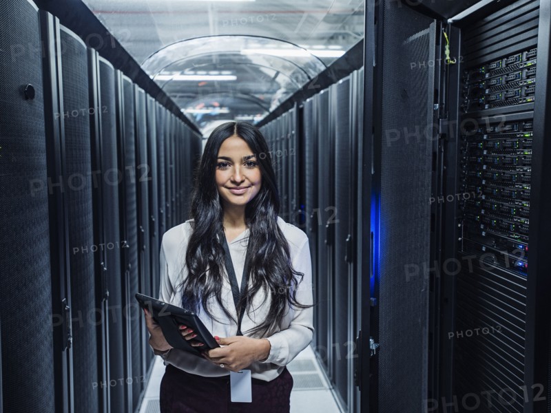 Mixed race technician holding digital tablet in server room