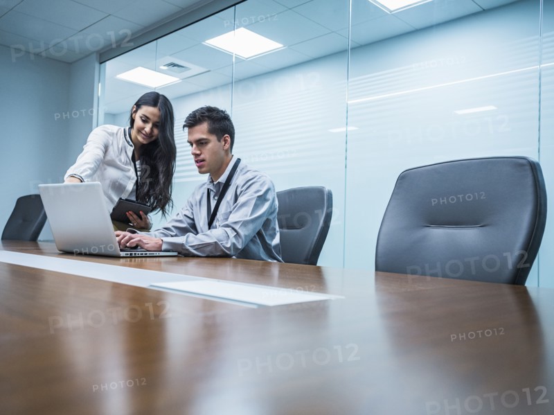 Business people using laptop in conference room