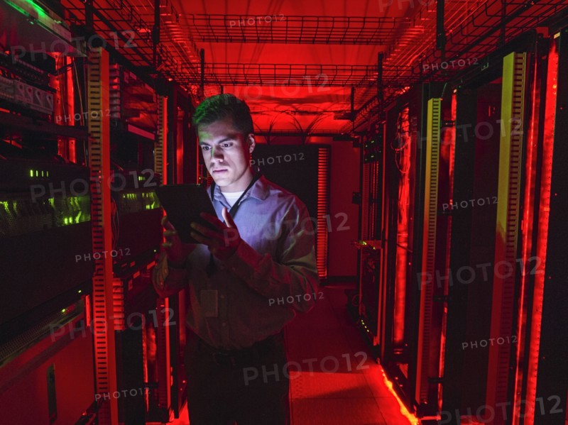 Hispanic technician using digital tablet in server room