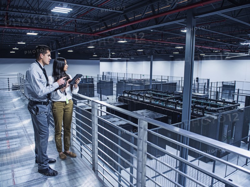 Business people examining server room from balcony