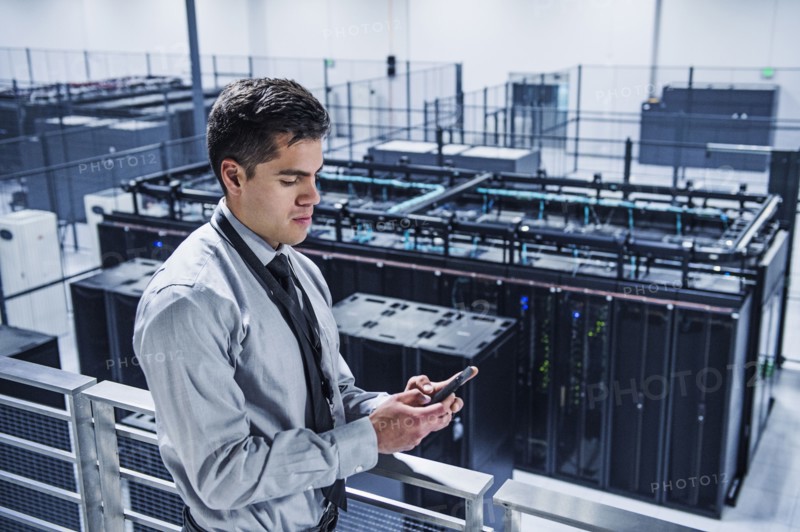 Hispanic businessman using cell phone on balcony over server room