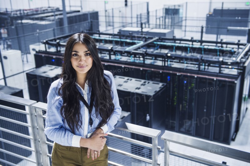 Mixed race businesswoman smiling on balcony over server room