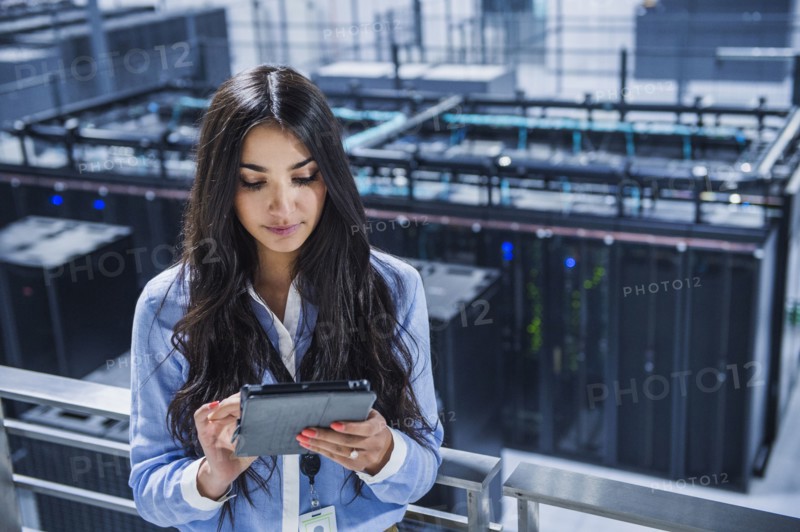 Mixed race businesswoman using digital tablet on balcony over server room