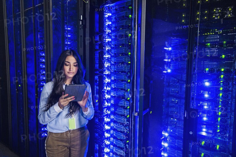 Mixed race technician using digital tablet in server room