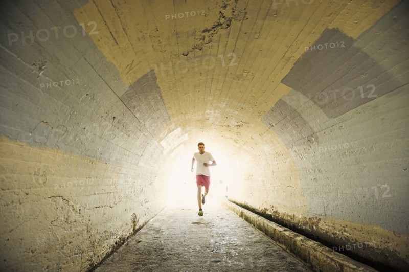 Caucasian man jogging in tunnel
