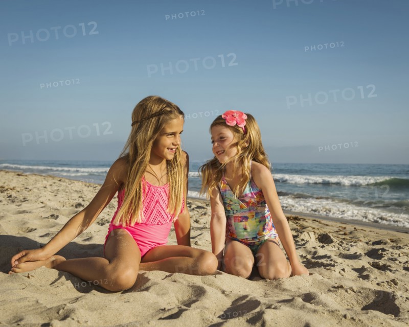 Caucasian sisters smiling on beach