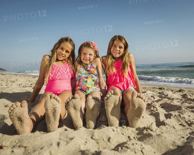 Caucasian sisters with sandy feet on beach