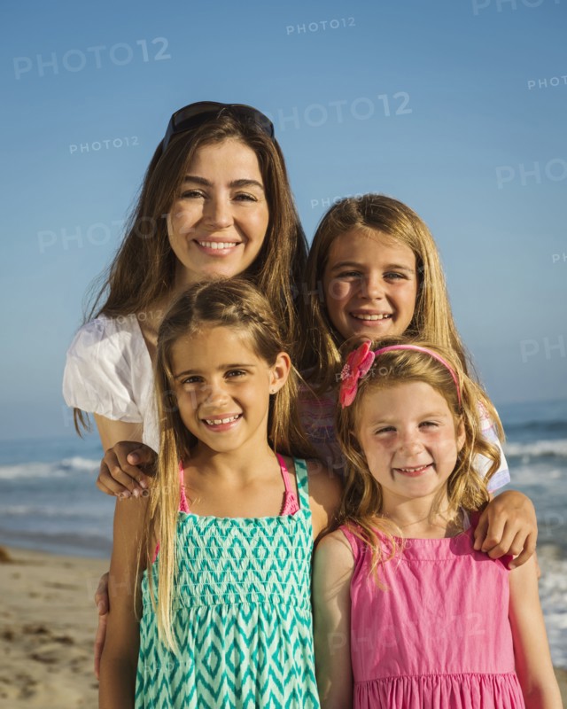 Caucasian mother and daughters smiling on beach