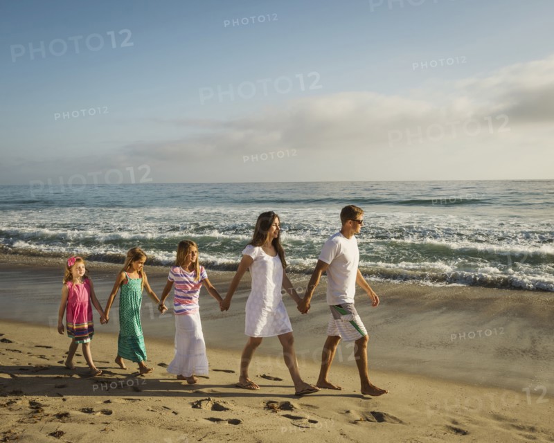 Caucasian family holding hands on beach