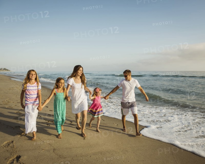 Caucasian family holding hands on beach