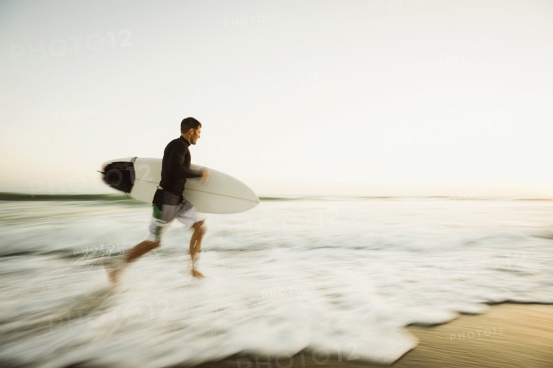 Caucasian man carrying surfboard on beach